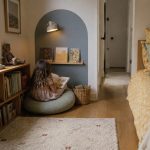 A child reading in a compact bedroom nook with low wood book storage and a clear walkway